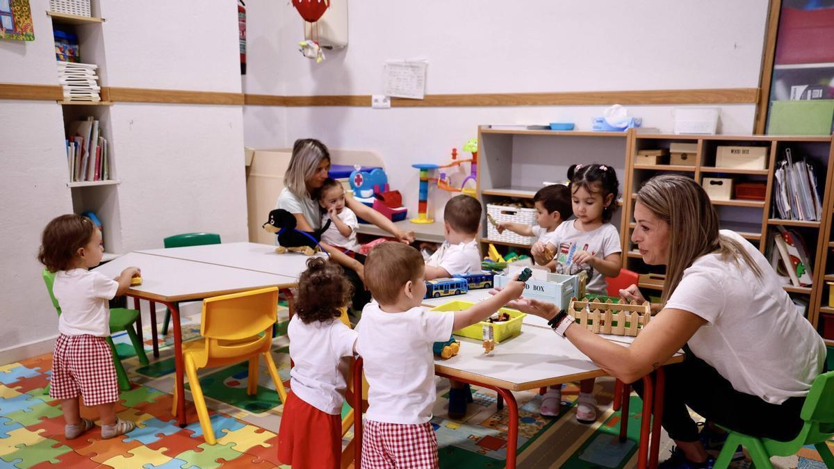 Dos profesores juegan con alumnos de una escuela infantil.