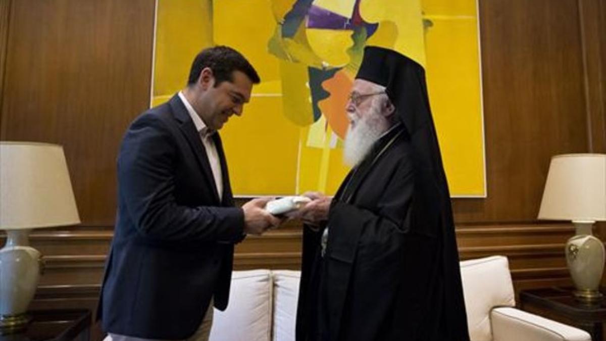 Tsipras (izquierda) recibe un regalo del arzobispo Anastasios de Albania, en su encuentro en Atenas, este martes.