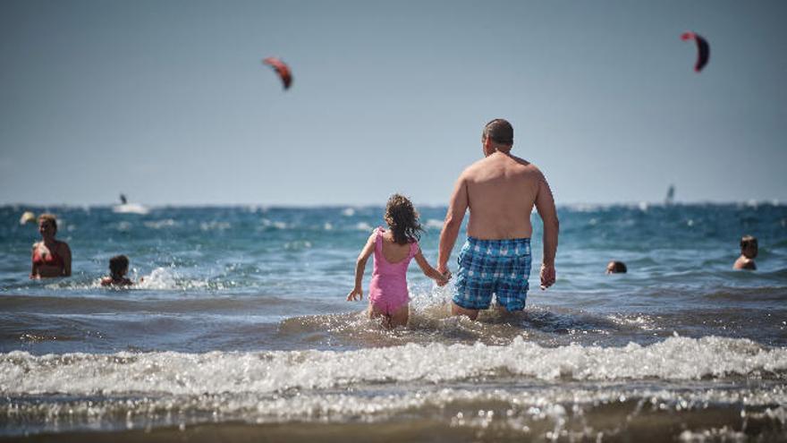 Un padre y una hija se adentran al mar en El Médano.