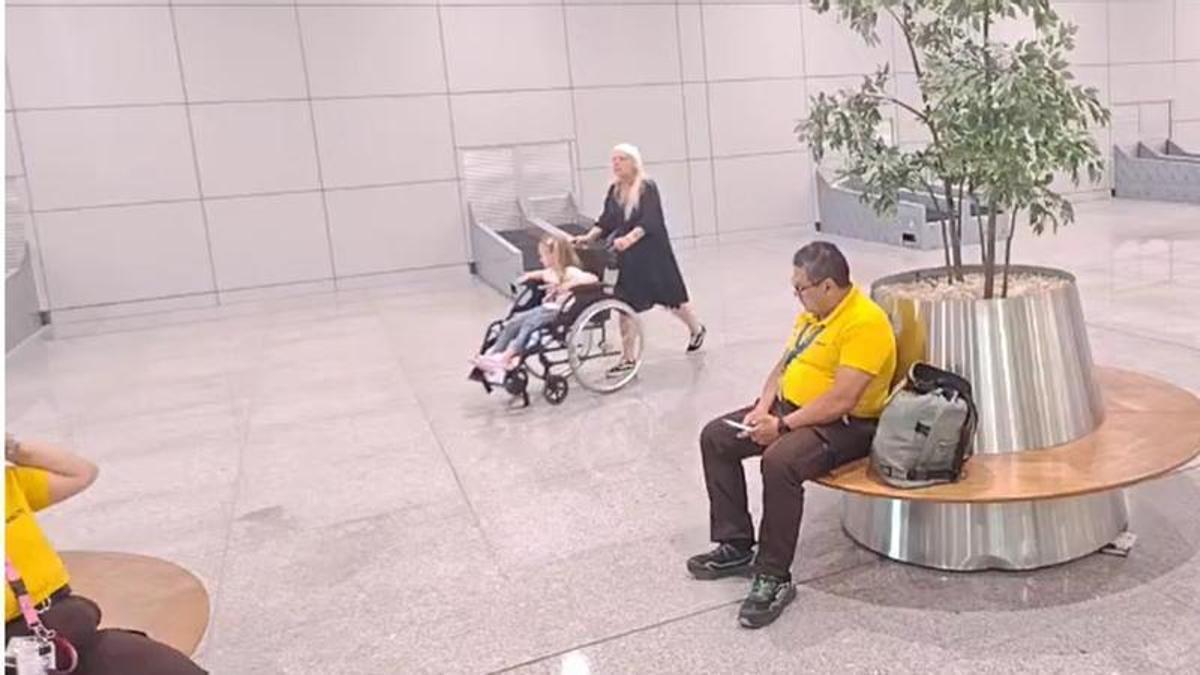 Trabajadores de PMR en huelga mientras una pasajera se encarga de trasladar a su familiar por la terminal del aeropuerto de Palma.