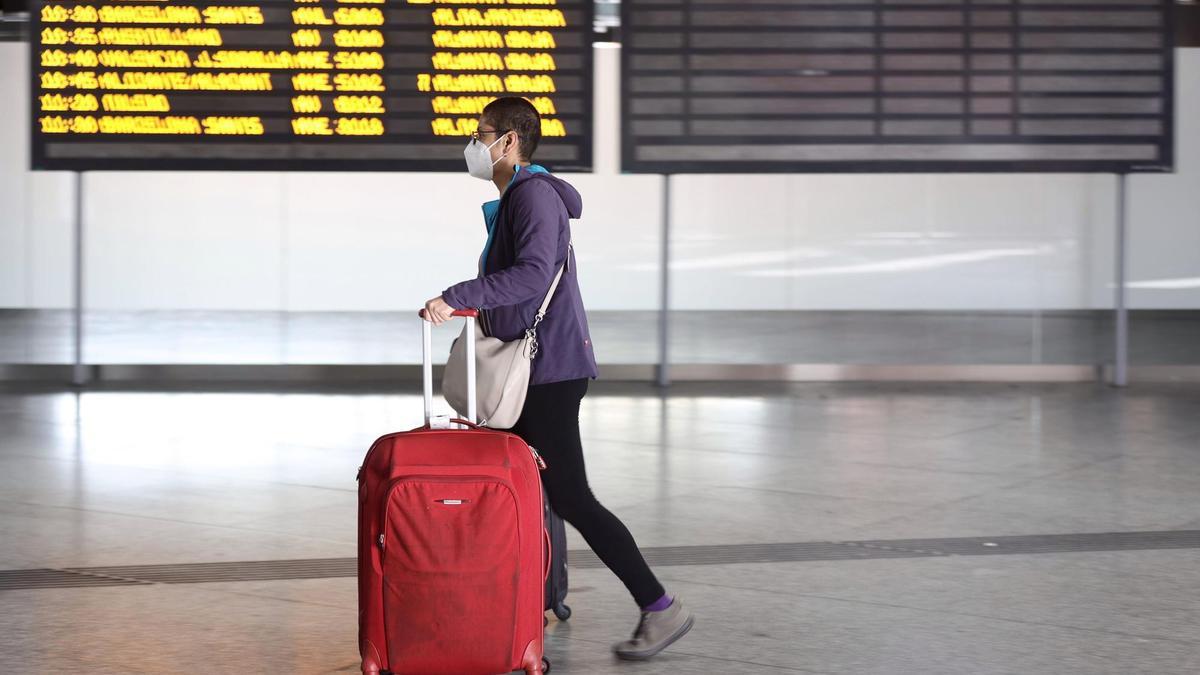 Archivo - Una chico, con maletas, pasa junto a un panel de salidas con diferentes destinos en Atocha