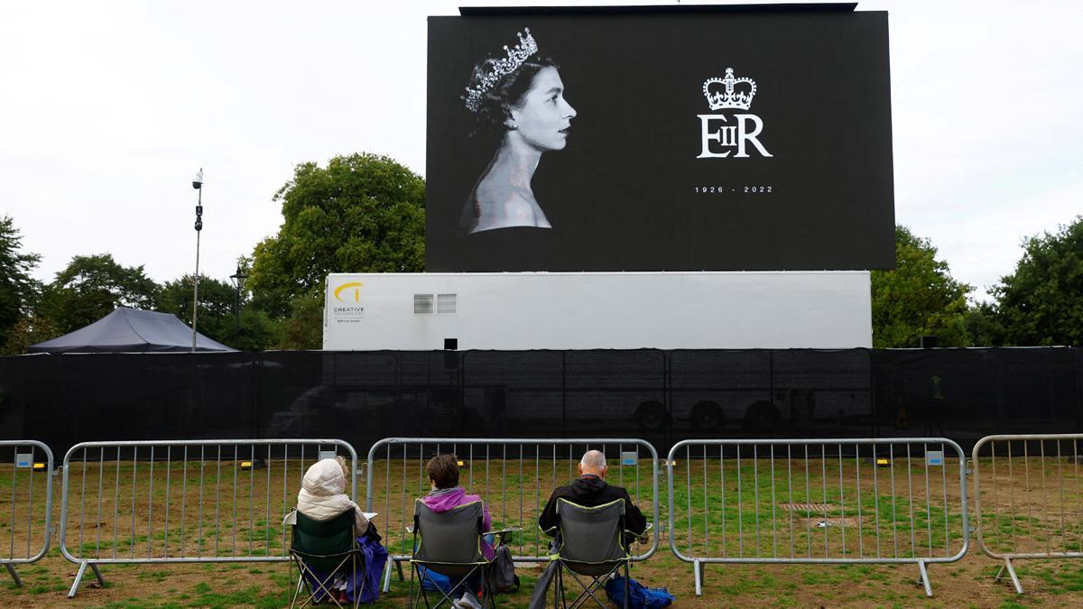 Ciudadanos sentados en Hyde Park, en Londres, frente a una pantalla donde podrá verse el traslado del féretro de Isabel II.