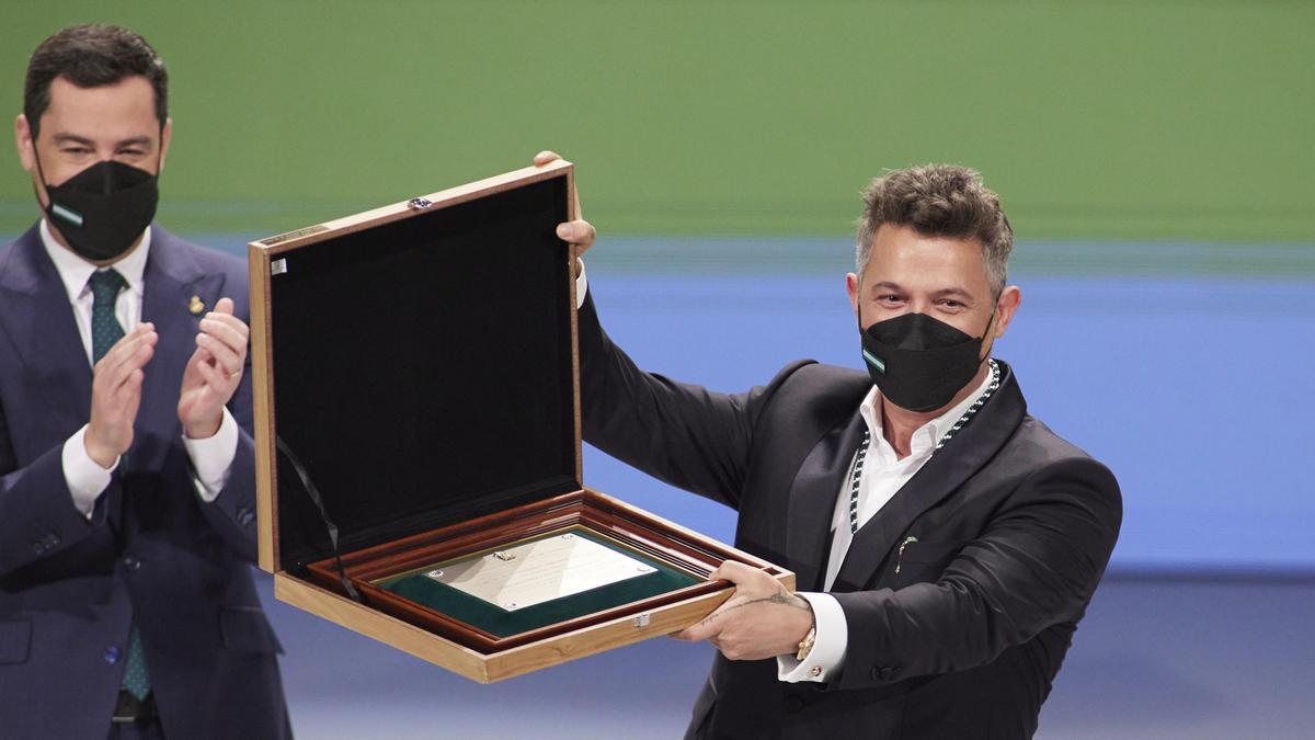 El presidente de la Junta, Juanma Moreno, (i) entrega el título de Hijo Predilecto de Andalucía al cantante, Alejandro Sanz, (d) durante el acto de entrega de Medallas de Andalucía 2022 en el Teatro de la Maestranza, a 28 de febrero de 2022 en Sevilla (An