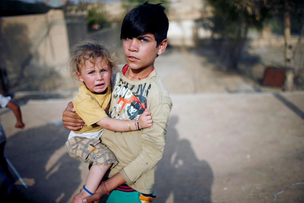 Un menor de Yazidi sostiene a su hermana en un patio en la región de Sinjar, Iraq