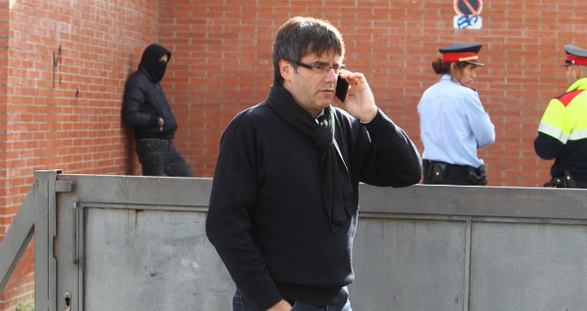 L’alcalde de Girona, Carles Puigdemont, trucant per telèfon mòbil, al fons un detingut i dos Mossos d’Esquadra.