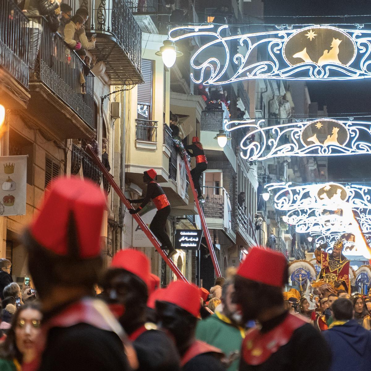 Los pajes suben por largas escaleras hasta los balcones para entregar los regalos