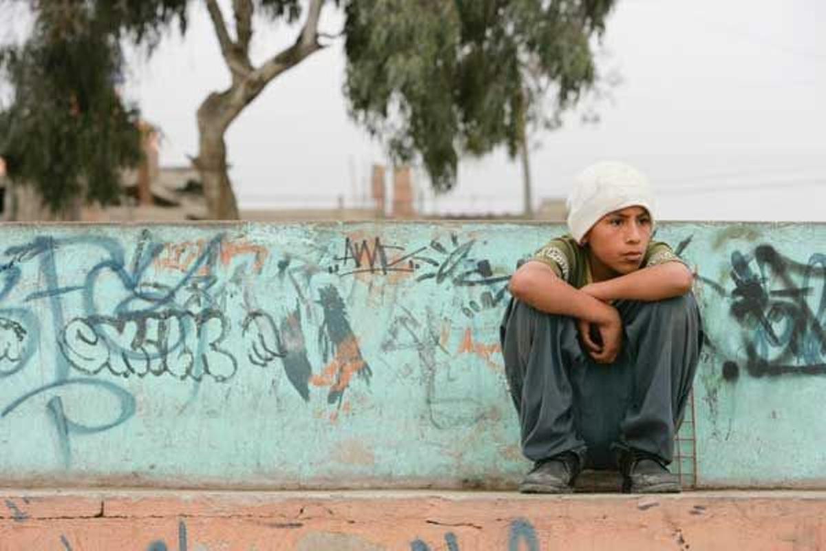 Un chico peruano sentado sobre un muro en Lima