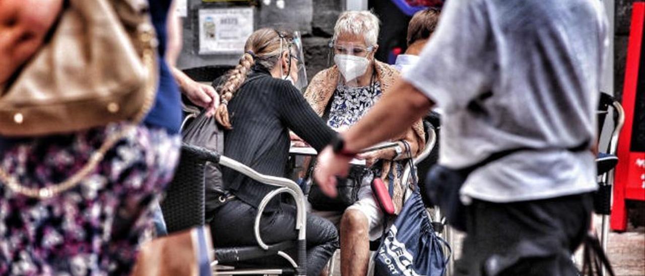 Dos personas, sentadas en una terraza de Santa Cruz, con mascarillas para evitar la propagación de la Covid.