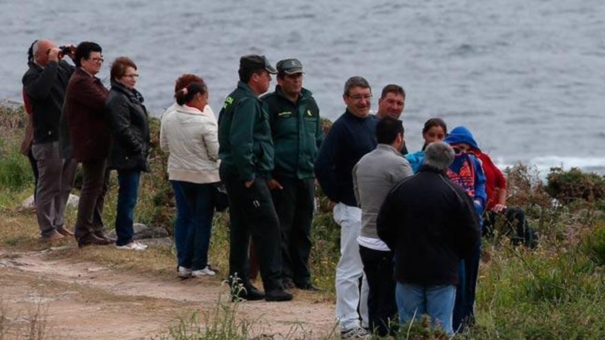 La Guardia Civil examina la costa rodeada de curiosos. / NICK