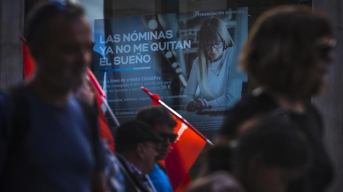 Publicidad de una entidad bancaria al paso de la manifestación, en Valencia.