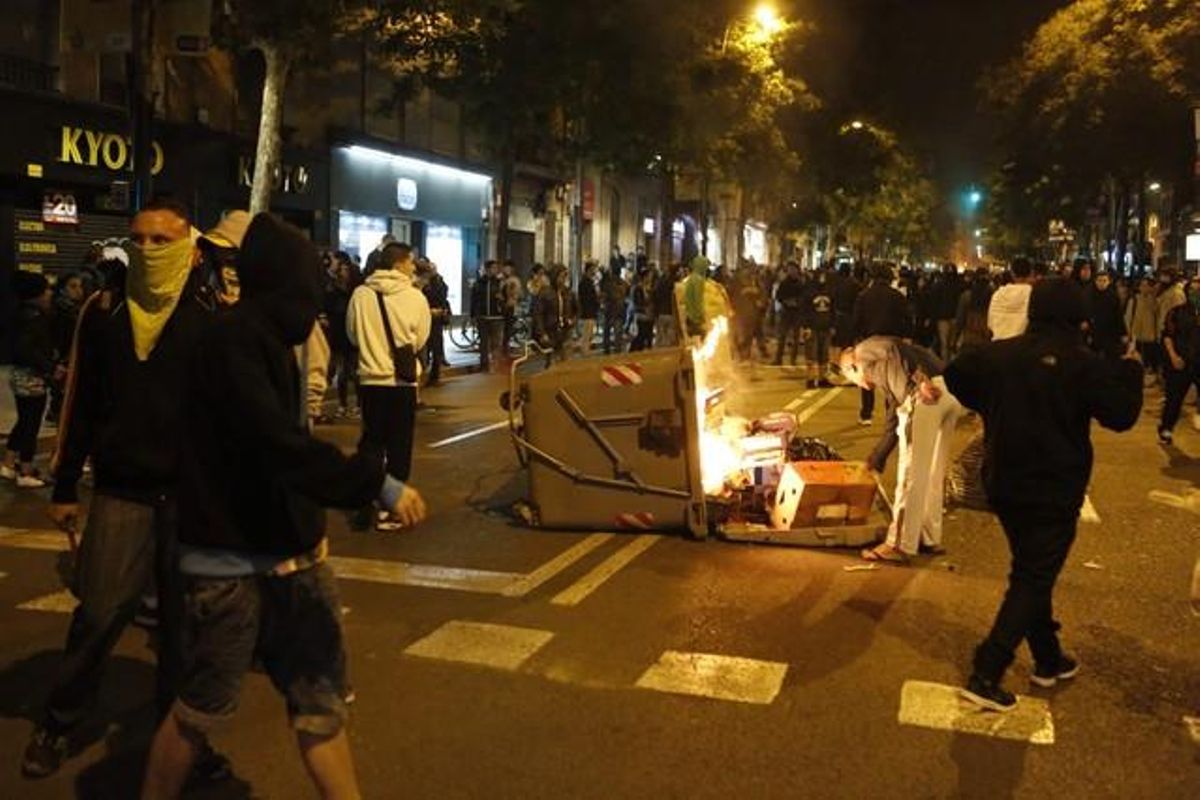 Moment en què uns violents calen foc a un contenidor, aquesta nit, al carrer de Sants.