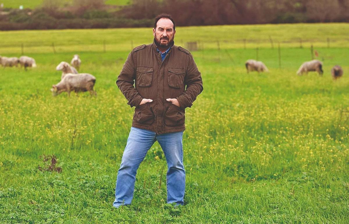 Felipe Molina, sexta generación ganadera de su familia, posa al aire libre con animales de La Albaida, al fondo.
