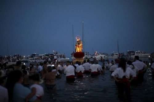 Men in traditional costumes carry a statue of the El Carmen Virgin into the sea during a procession in Malaga