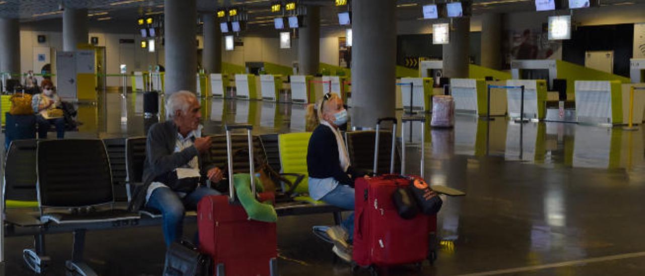 Varios pasajeros esperan en una de las salas de facturación del aeropuerto de Gando, en Gran Canaria.