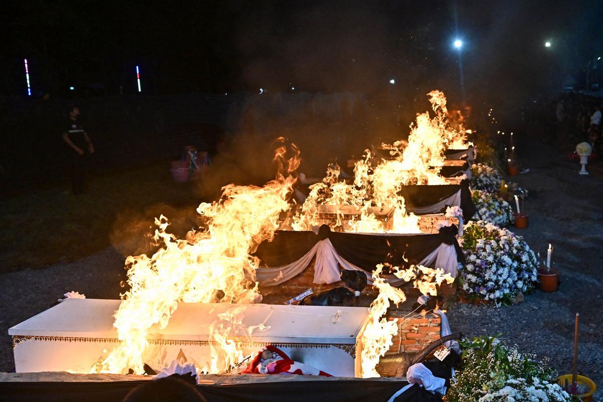 La gente observa cómo las piras funerarias incineran a 19 víctimas del tiroteo en la guardería de Uthai Suwan en el templo Wat Rat Samakee en Uthai Sawan. Un exoficial de policía disparó y mató a 37 personas, al menos 24 de ellos niños, después de irrumpir en una guardería infantil en el noreste de Tailandia.