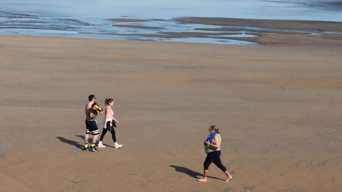 Paseantes al sol el jueves por la playa de Salinas, en Castrillón. | Mara Villamuza