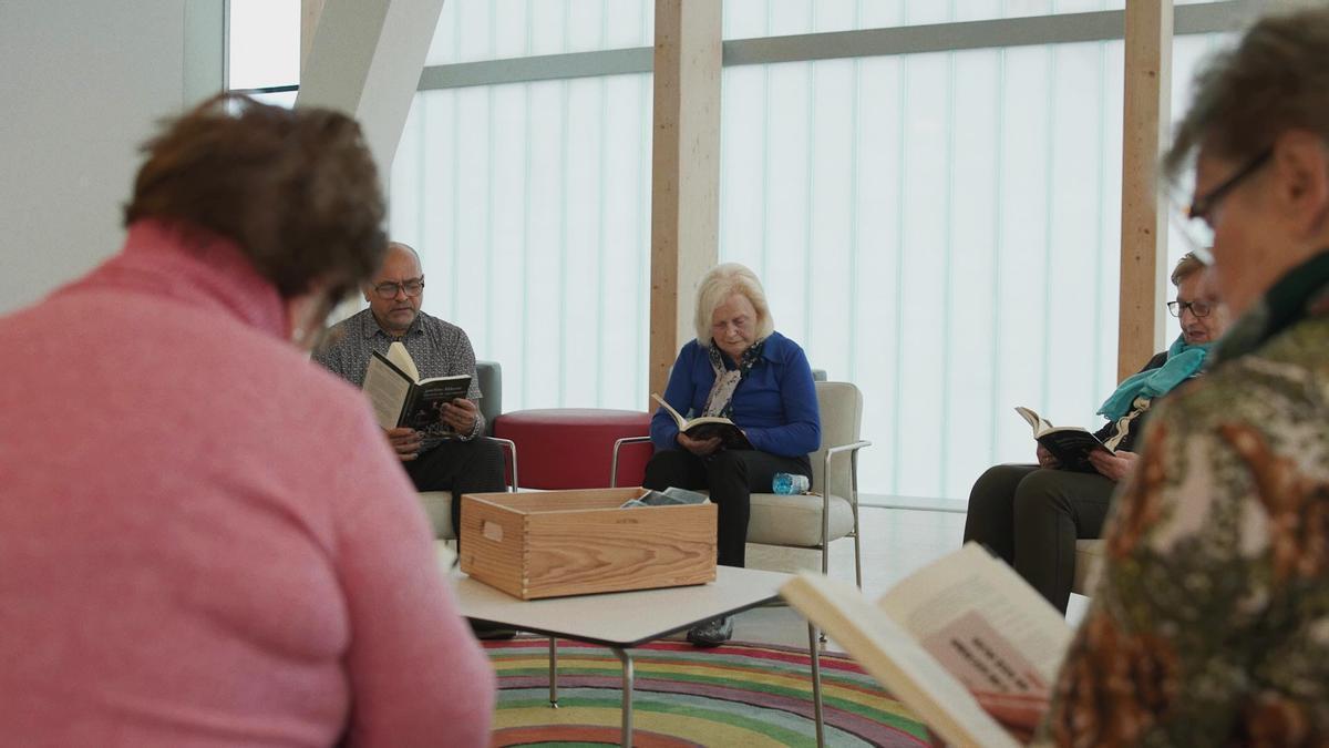 La voluntaria de 80 años, Teresa Guisán, lee un libro junto con su grupo de Lectura en voz alta en la biblioteca del Ágora.