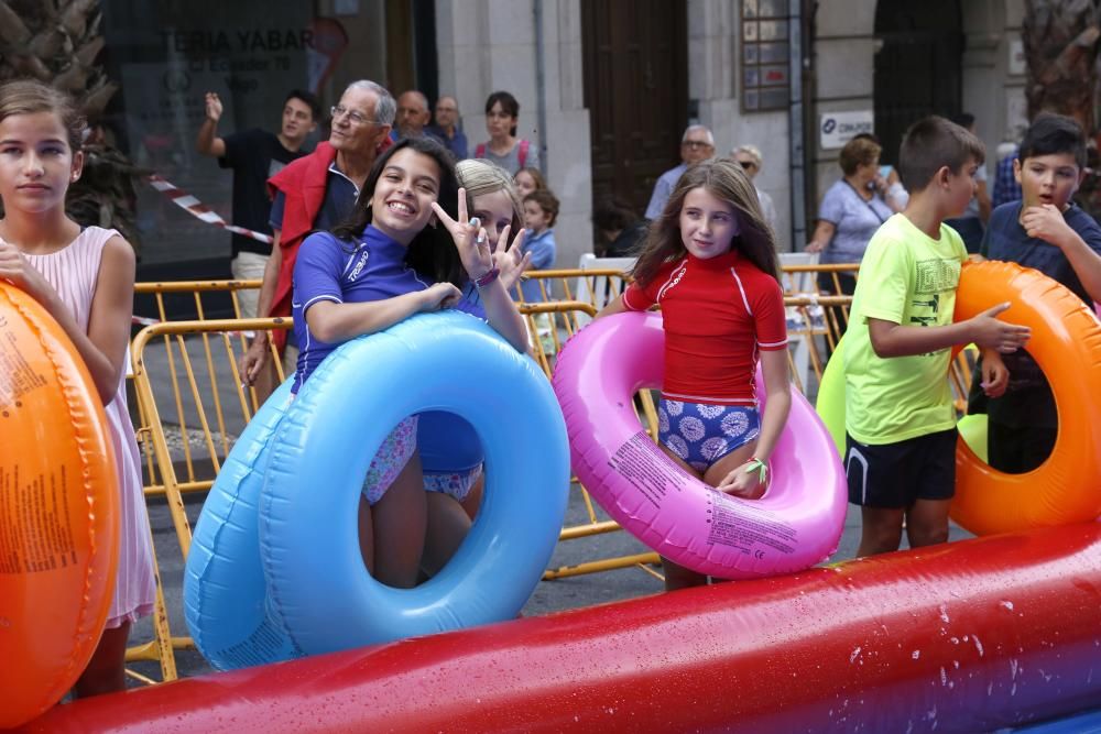 Cientos de personas disfrutan del tobogán acuático en la calle Colón