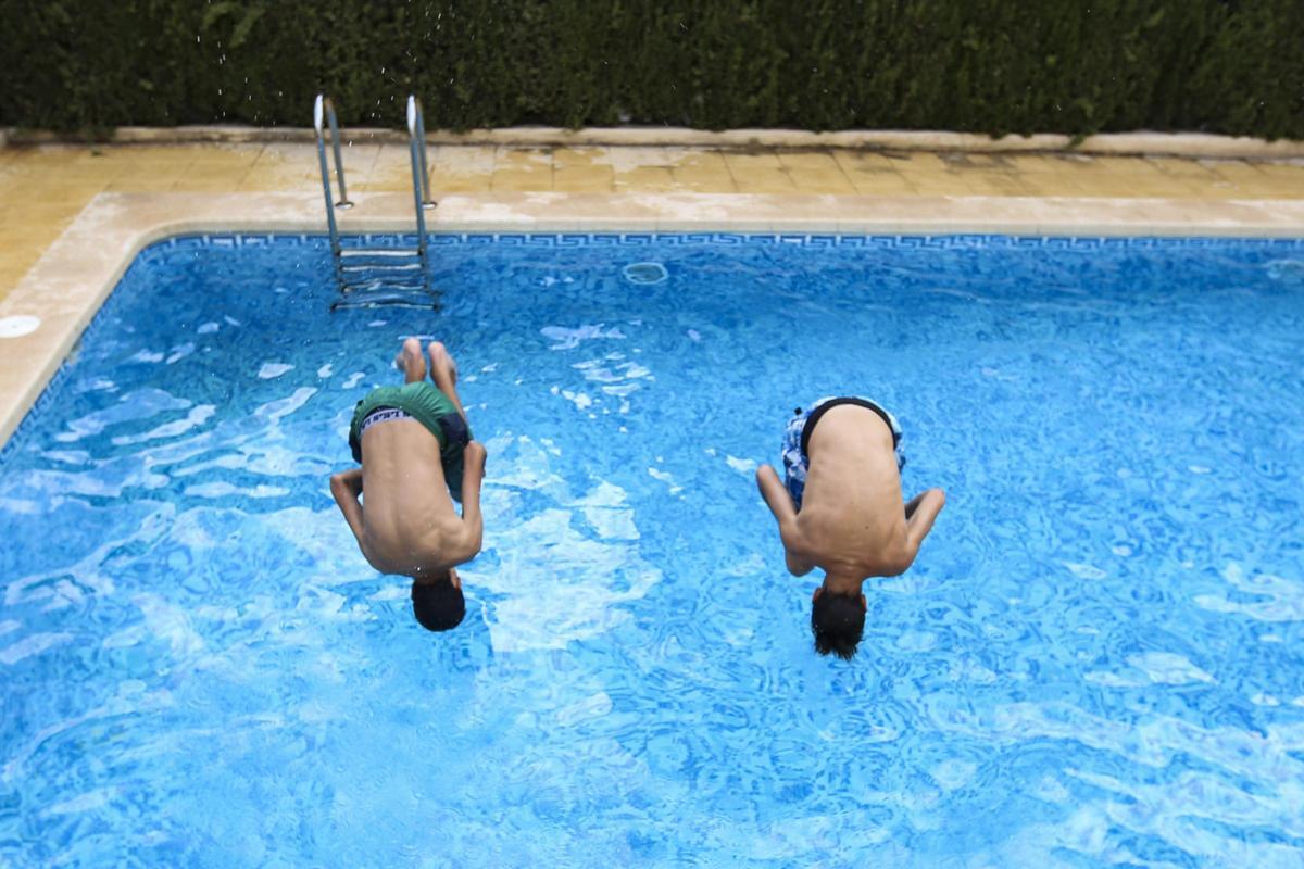 Dos jóvenes se dan un chapuzón en una piscina.