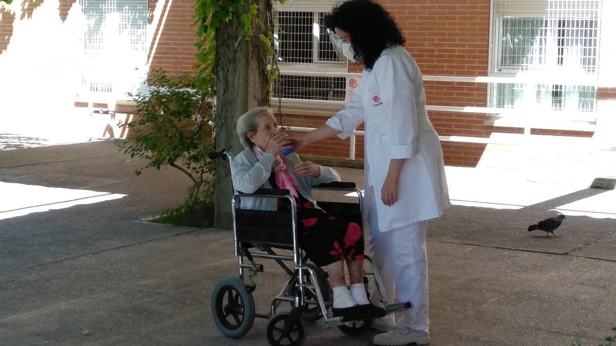 Una trabajadora de Cáritas atiende a una mujer en silla de ruedas.