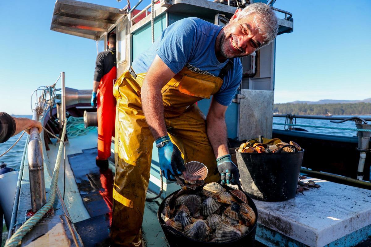 Un pescador muestra dos capachos de vieira.