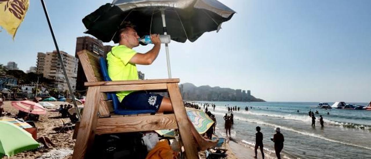 Un socorrista bebe agua bajo la sombrilla especial que reduce el calor en unos ocho grados.