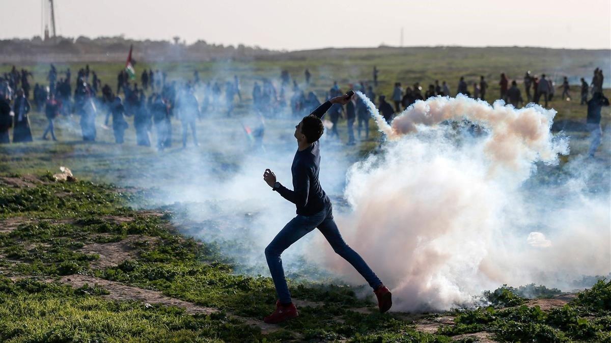 Un manifestante palestino lanza un bote de gas lacrimógeno hacia las fuerzas israelíes durante los enfrentamientos después de una manifestación en la frontera con Israel al este de la ciudad de Gaza.