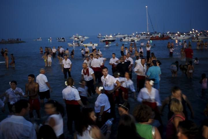 People take part in the procession of the El Carmen Virgin after it was carried into the sea in Malaga