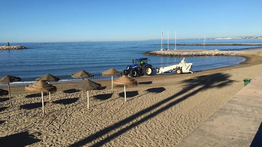 Un tractor allana la arena de la playa de El Faro, en el centro urbano de Marbella.