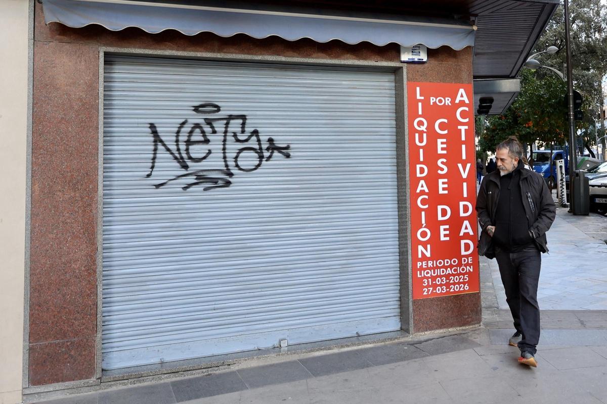 Un hombre pasa por la puerta de un negocio del centro de Murcia que está próximo a su cierre y con sus productos en liquidación.
