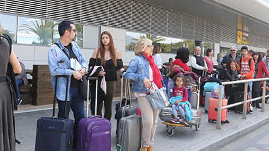 Un grupo de turistas hace cola en el exterior del aeropuerto de Ibiza a la espera de un taxi.