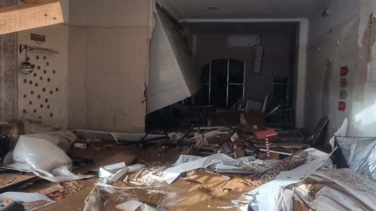 Estudio de fotografía destrozado en la localidad valenciana de Benetusser; donde se ve cómo la nevera industrial de la pescadería anexa ha traspasado el tabique