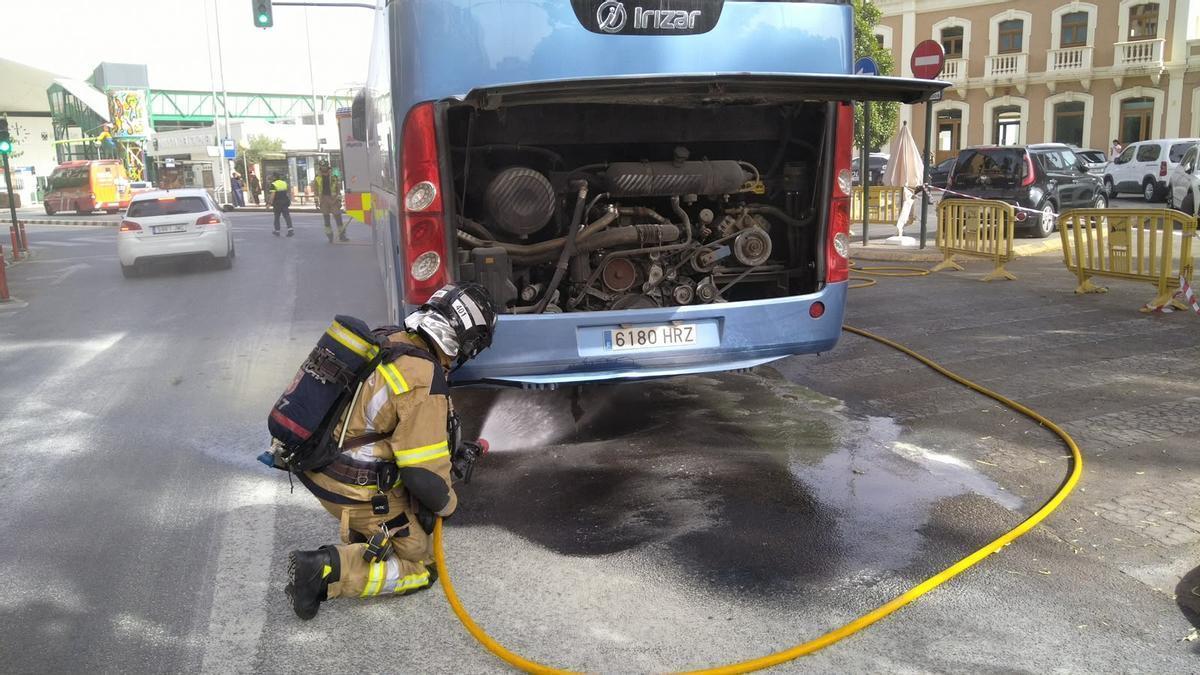 Un bombero rocía de agua el motor incendiado de un autobús junto a la Estación del Carmen, en Murcia.