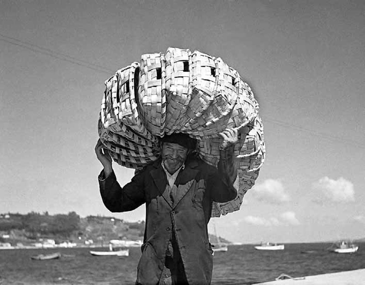 Un mariñeiro de Bueu cargado  de patelas, coa Praia de Beluso ao fondo.