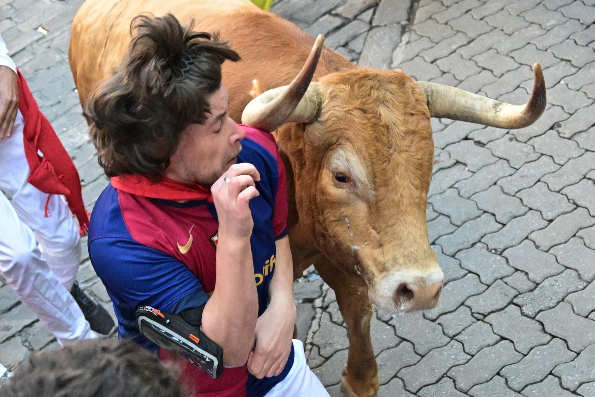 PAMPLONA, 09/07/2025.- Un toro de la ganadería Álvaro Núñez roza a uno de los mozos durante el tercer encierro de los Sanfermines 2025 este miércoles en Pamplona. EFE/Daniel Fernández