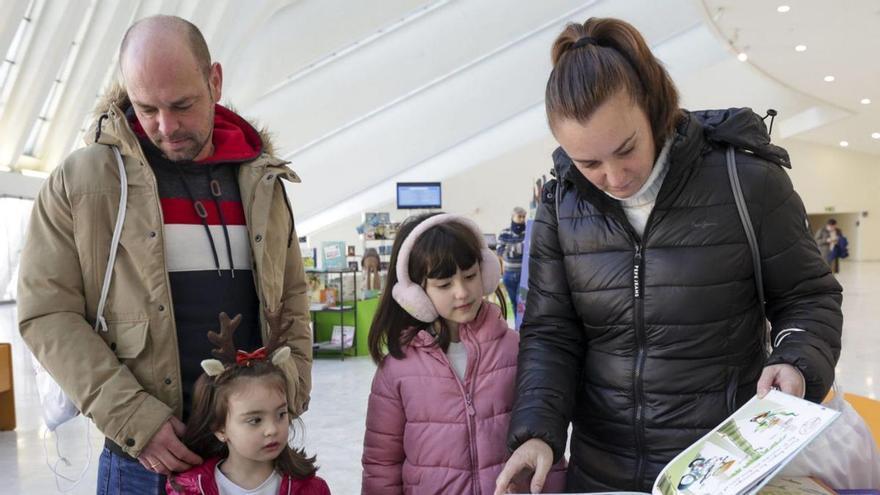 Adrián Alonso y Tamara del Cuadro, con sus hijas Llara y Leire, mirando varios libros.