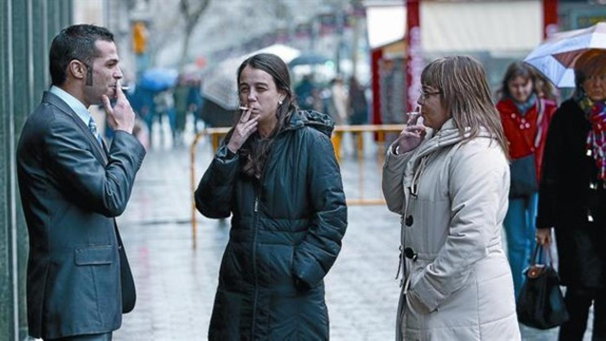 Bajo la lluvia 8 Un grupo de fumadores, ayer, en una calle de Barcelona.