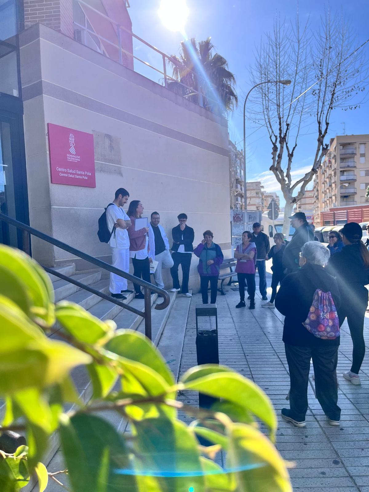 Los asistentes atienden a la charla con consejos de salud de los técnicos del centro de salud de Santa Pola antes de la caminata saludable