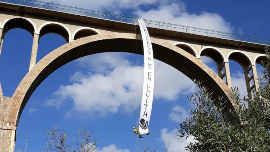 Los dos bomberos en el momento de desplegar la pancarta en el puente