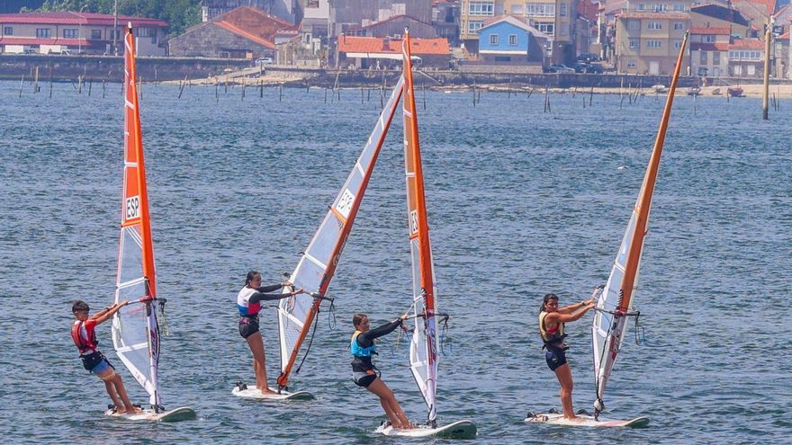 Los surfistas en plena regata con Carril al fondo. |  Iñaki Abella