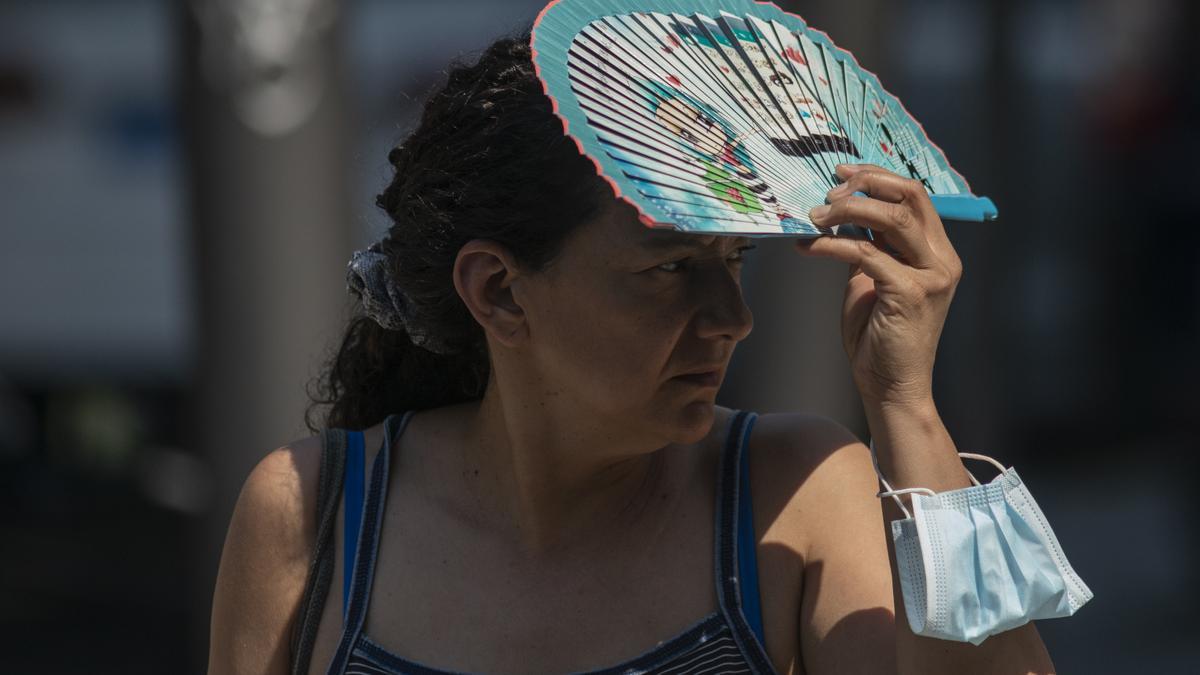 Una mujer se protege del sol con un abanico.