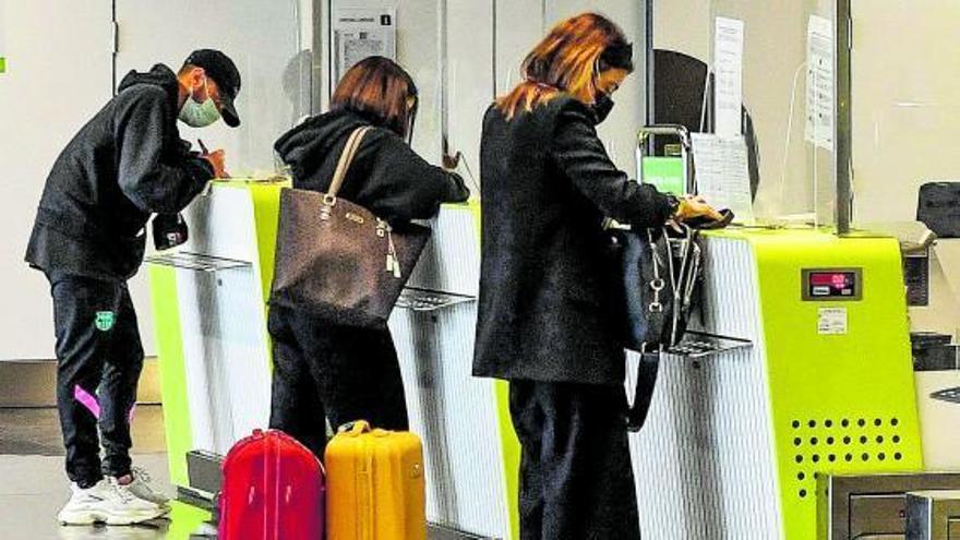 Tres pasajeros facturan en los mostradores de un aeropuerto. | | JUAN CASTRO