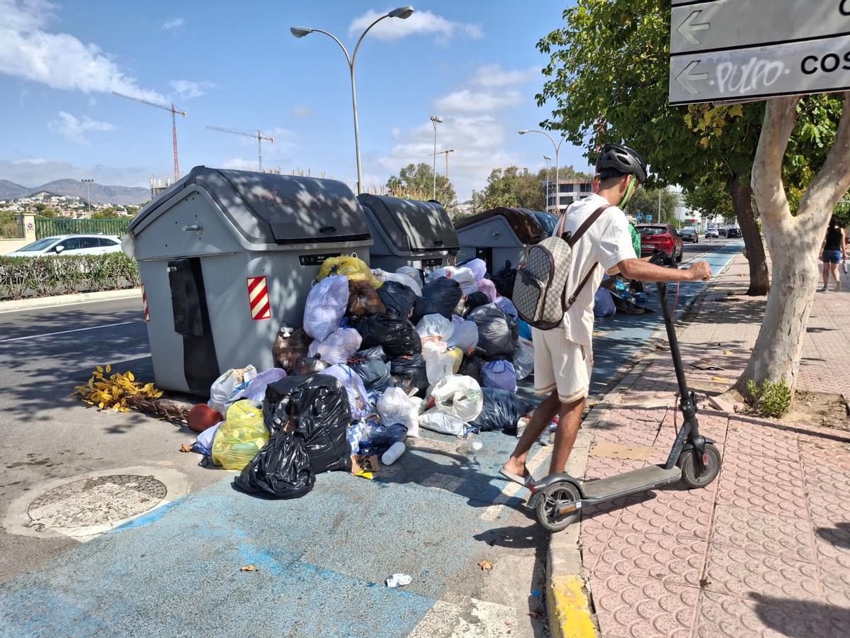Un joven se baja del patinete para esquivar la basura, que bloquea el carril bici