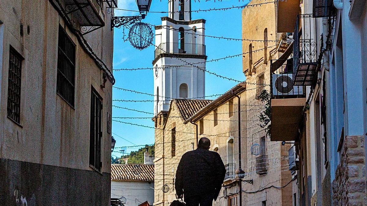 Una persona camina por Sella, arriba, y dos de los ocho núcleos urbanos de la Vall de Gallinera. | D. REVENGA / J. RUZ