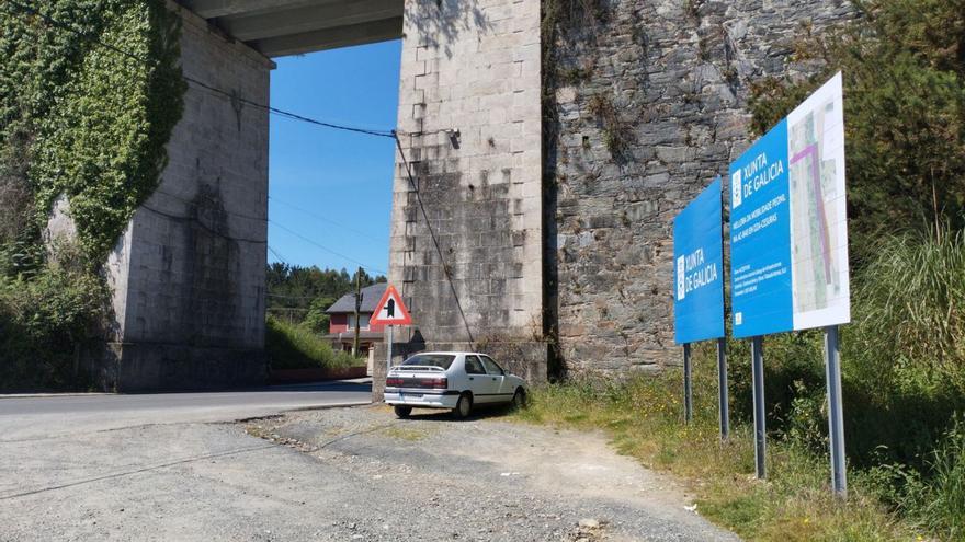 Carteles que anuncian la obra junto al talud del tren en Oza-Cesuras.