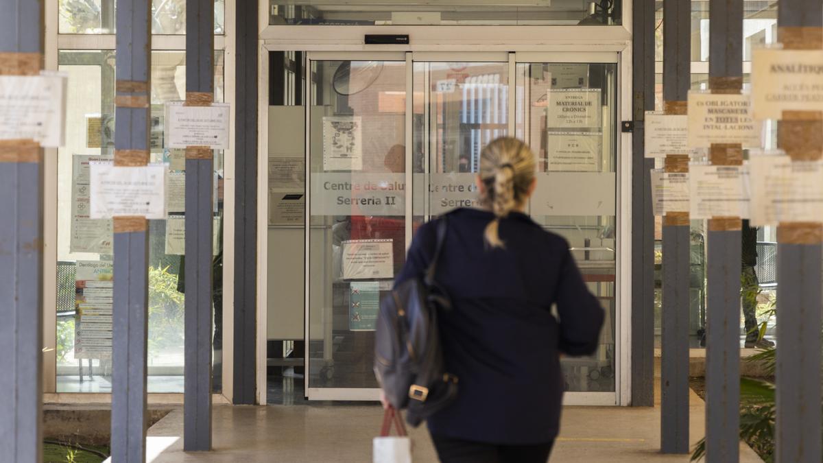 Una mujer accede al centro de salud de Serrería II ayer, entre un mar de carteles con avisos.