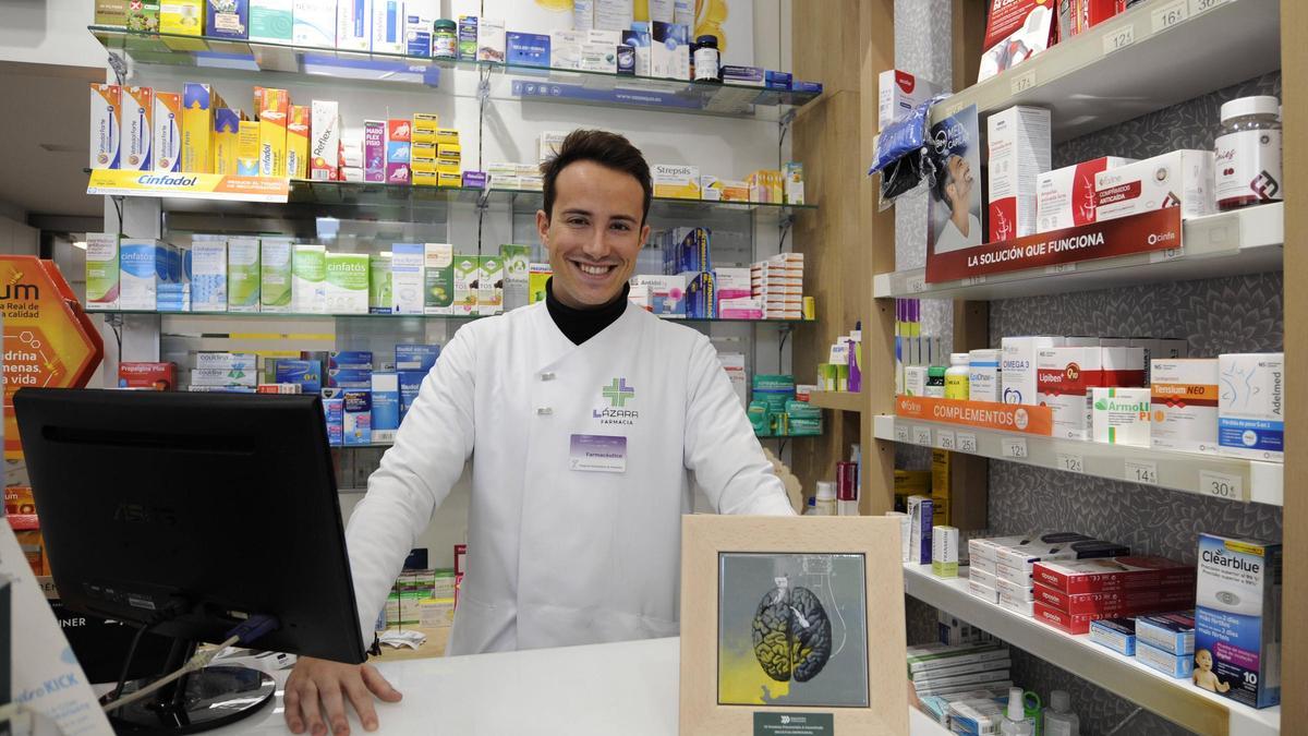 Alberto Lázara co seu premio da Deputación na súa farmacia de Prado.