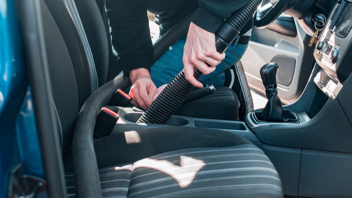 Hombre limpiando el interior de un coche con aspiradora profesional