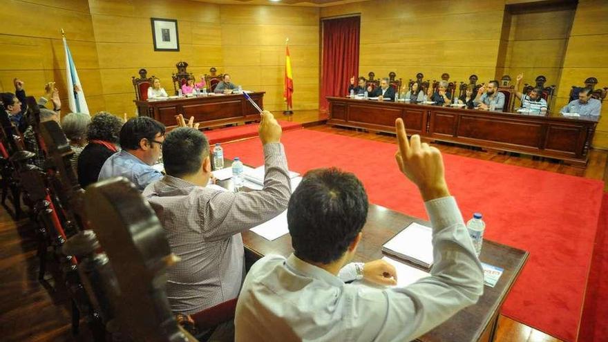 Abal, en primer término, vota levantando la mano en un pleno de Cambados. // Iñaki Abella