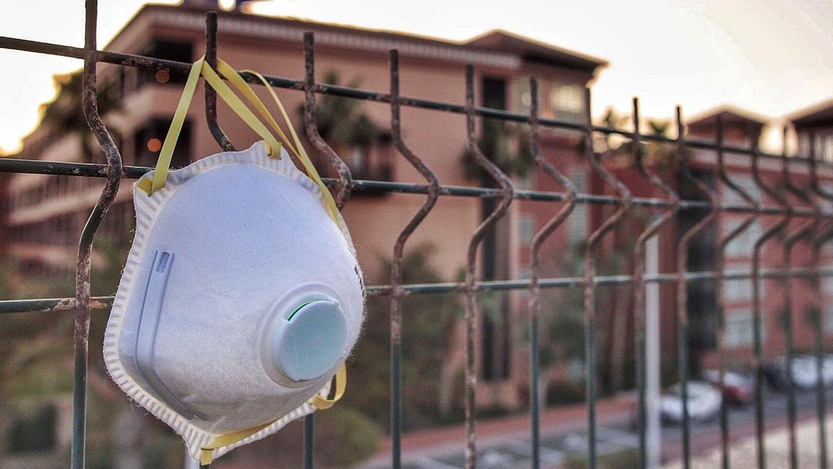 Una mascarilla cuelga de la verja del hotel de Adeje en el que se produjo el primer brote del Covid-19 en Canarias, en febrero.